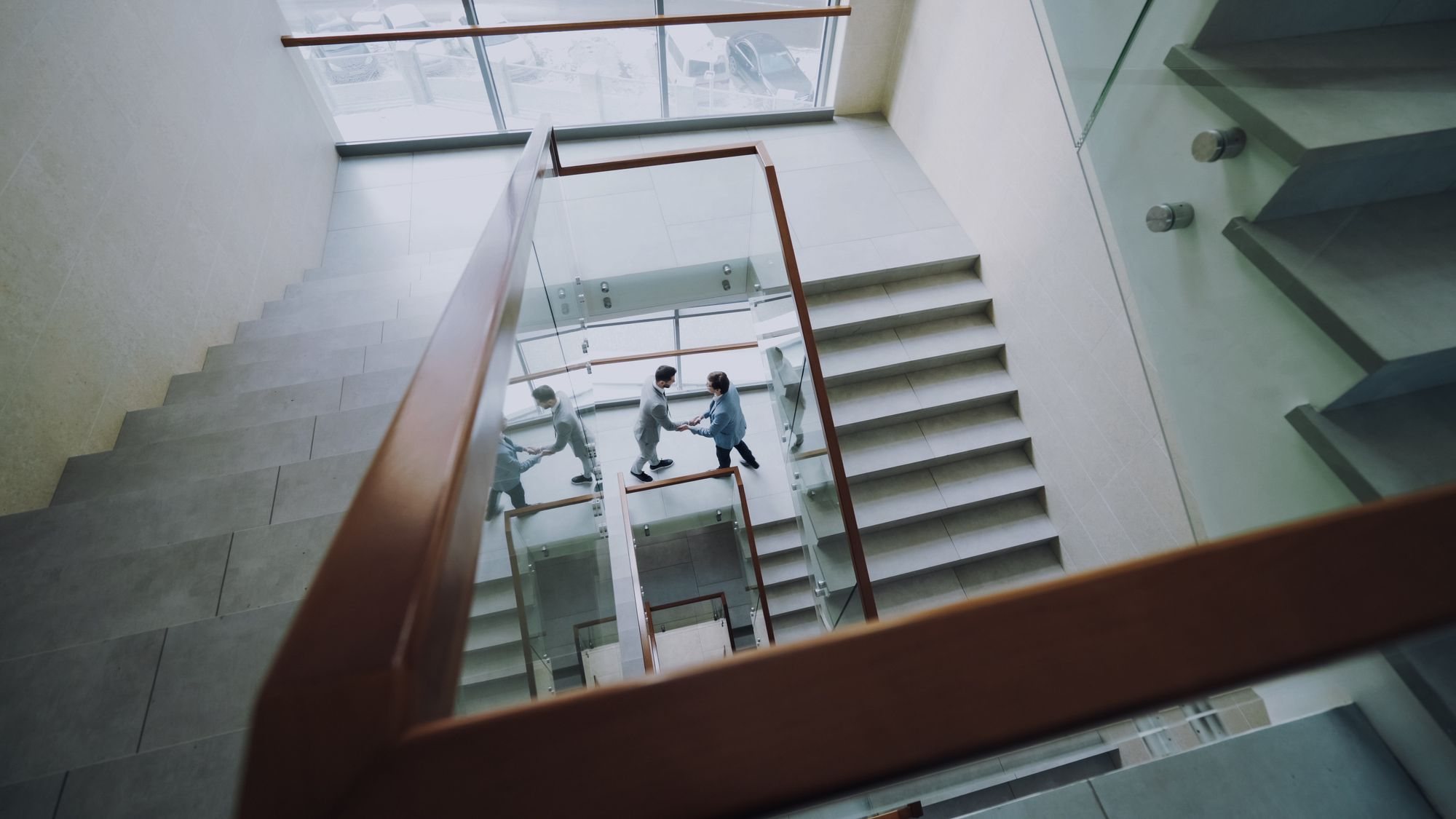 Two professionals meeting on a staircase in a modern office building